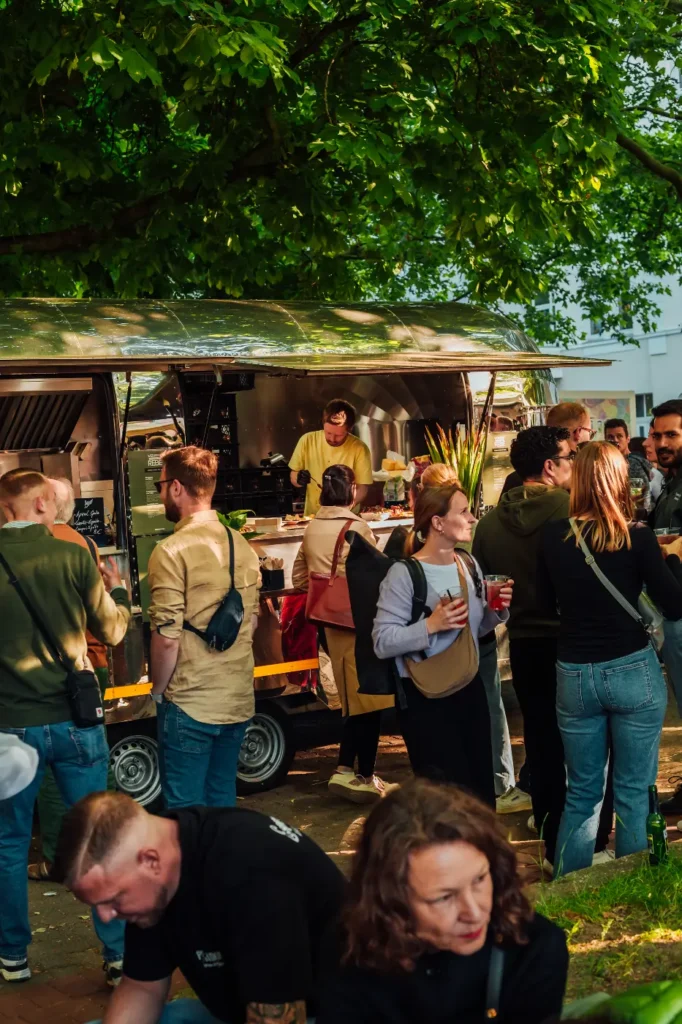 Menschen versammeln sich um einen Food Truck und genießen köstliche Speisen in geselliger Atmosphäre.